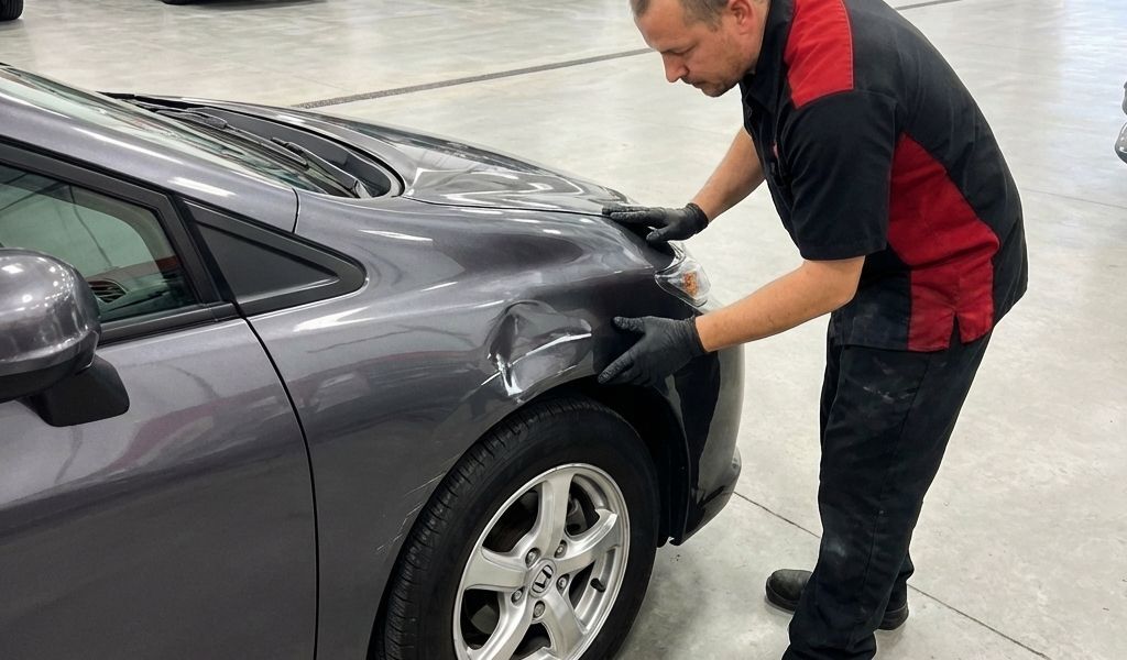 Lake Bluff Auto Body Shop tech inspecting damaged fender